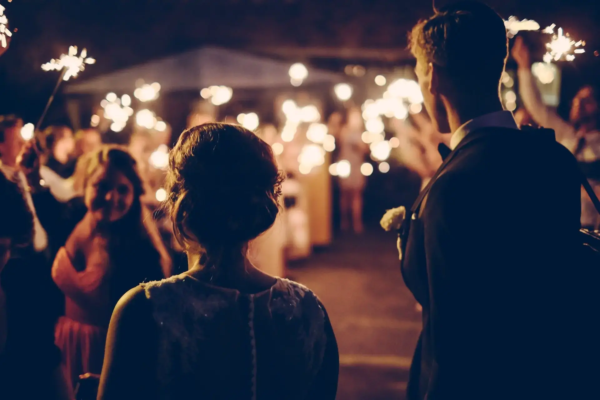 Couple enjoying a wedding celebration surrounded by guests holding sparklers, symbolizing luxury event experiences in Indianapolis.